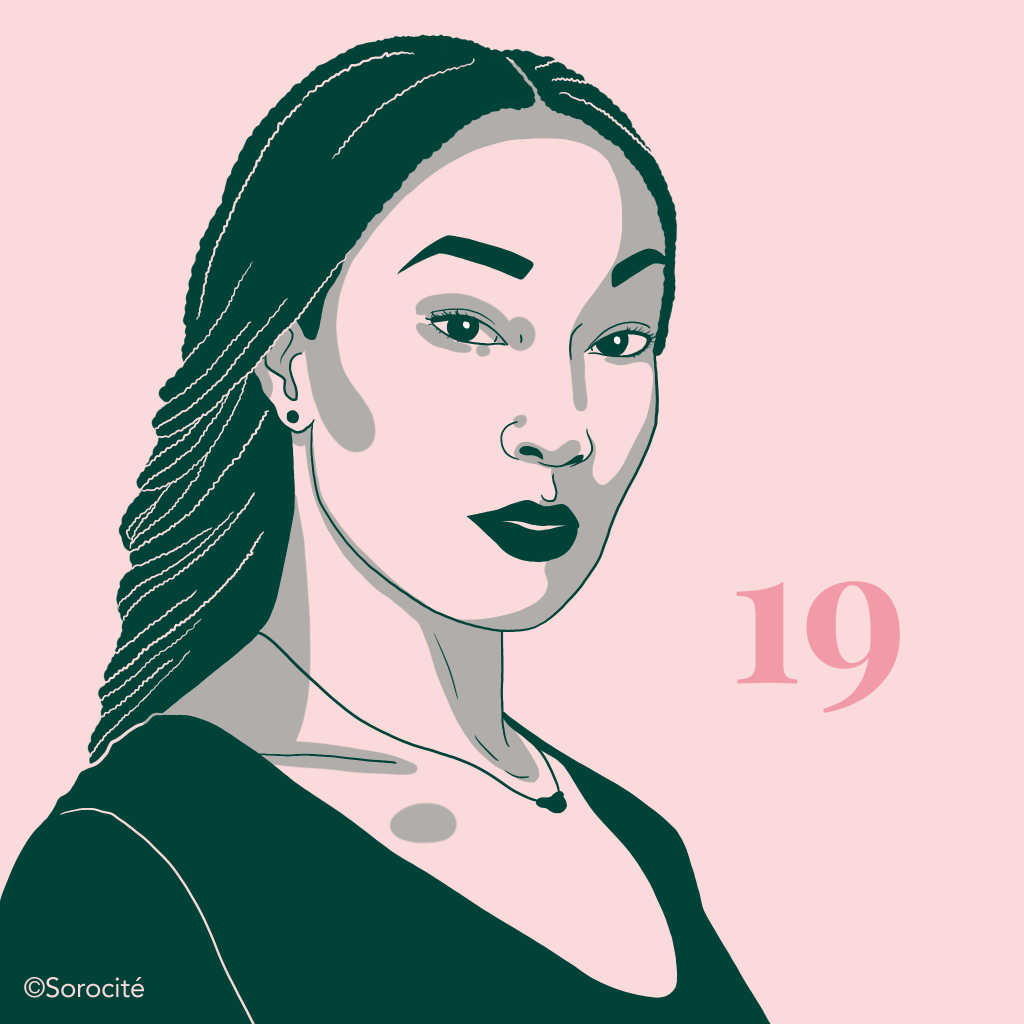 L'actrice en format portrait légèrement de biais, les cheveux nattés en arrière, portant un léger collier et un col en V avec le numéro 19 à droite. 
